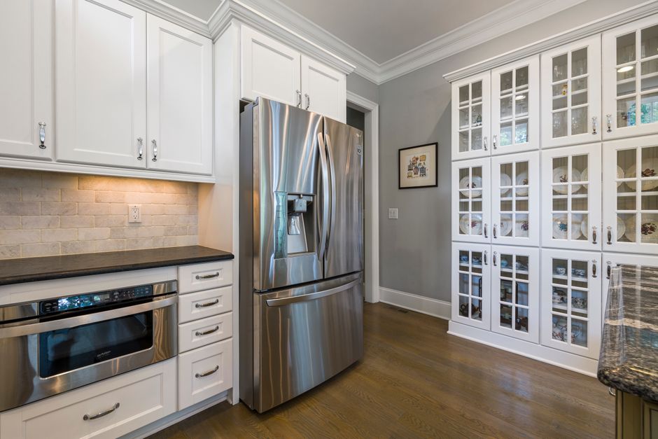 Contemporary kitchen interior featuring stainless steel fridge and white cabinets.